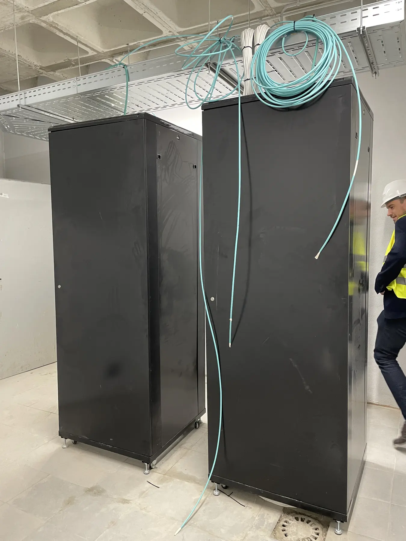 Two black equipment cabinets and overhead cabling in a residence data room